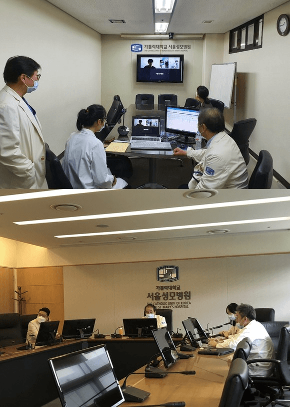 Two images show medical professionals at St. Mary’s Hospital in Seoul conducting remote health consultations. The top image features several doctors in a consultation room, engaging with a patient on a computer screen. The bottom image displays a conference room setting, with medical staff gathered around monitors, reviewing patient information and discussing health services. All individuals are wearing masks, highlighting safety measures during remote consultations.