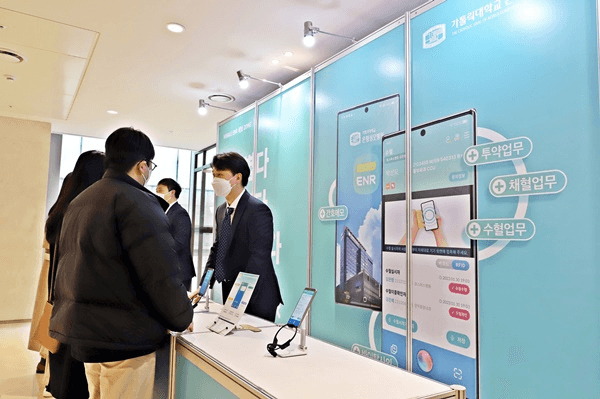 Attendees engage with representatives at a booth showcasing the VoiceEMR+ mobile nursing record platform during the VoiceEMR+ UNPACKED 2023 event, surrounded by promotional materials highlighting features and functionalities.